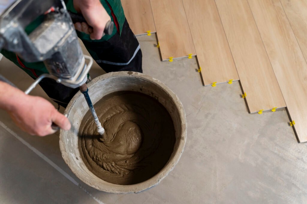 Photo d'un artisan qui fait de la colle sous du parquet