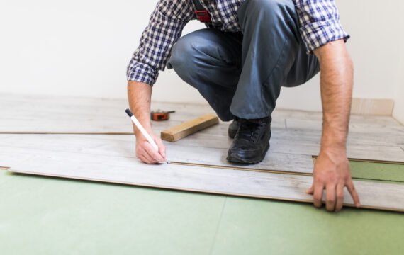 Photo montrant un artisan posant du parquet sur du carrelage