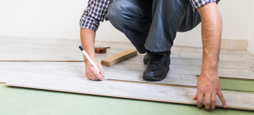 Photo montrant un artisan posant du parquet sur du carrelage