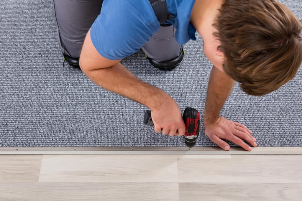 Photo d'un artisan en train de poser du parquet sur une moquette